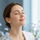 Close-up portrait of a content woman with a serene, relaxed smile, eyes closed, conveying relief and tranquility against a so
